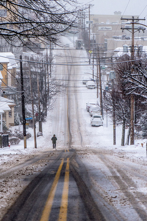 A lone man walks the snow covered streets of Mt. Washington in Pittsburgh