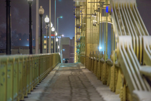 A lone person walks on the snow covered Clemente Bridge in Pittsburgh