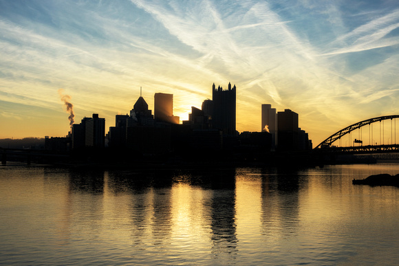 Light bursts through downtown Pittsburgh during a beautiful sunrise from the banks of the Ohio River