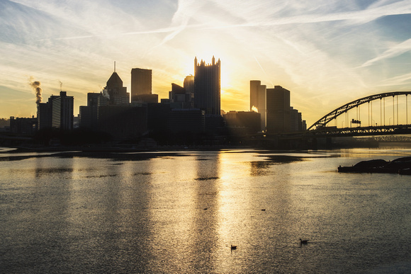 Golden sunlight bursts through Pittsburgh from the banks of the Ohio River