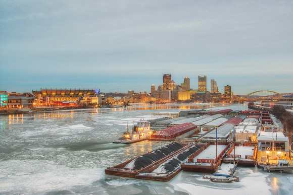 Barges glow on the icy Ohio River Pittsburgh in the winter