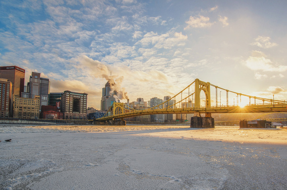 Sun through the Roberto Clemente Bridge with the Allegheny River covered in ice