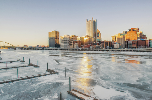 Sun reflecting off Pittsburgh skyline in the iced over Monongahela River from the Smithfield St Bridge