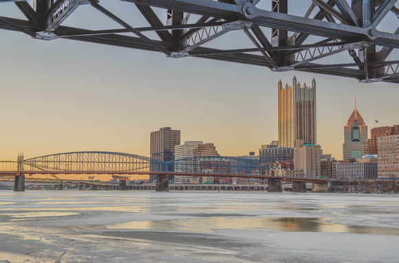 Pittsburgh framed by trolley bridge on the Monongahela River covered in ice