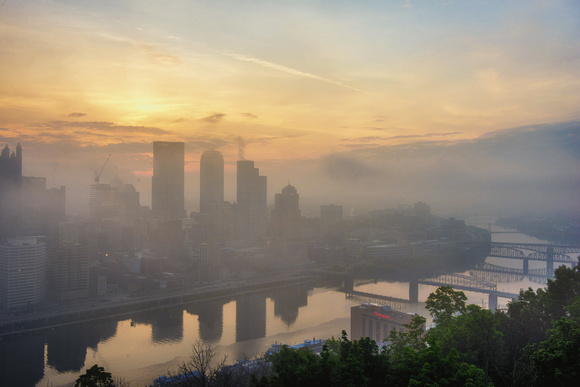 The sun rises over a foggy Pittsburgh skyline