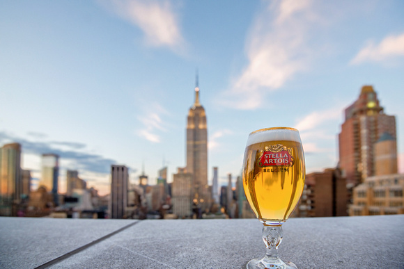 A Stella Artois sits on the edge of 230 Fifth Avenue as the Empire State Building rises in the background in New York City