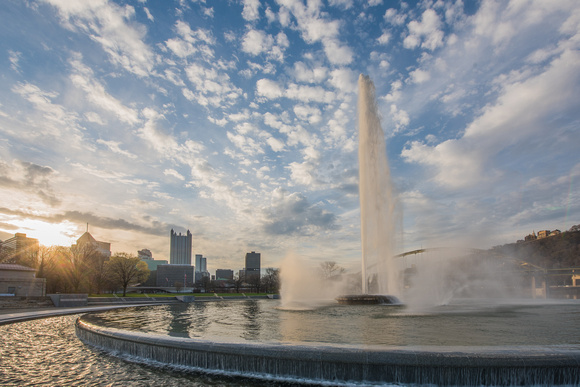 The sun glows over the Pittsburgh skyline at dawn by the fountain at Point State Park