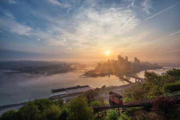 The sun shines through the fog over the Pittsburgh skyline