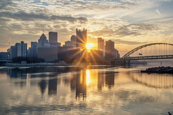 Sun burst through the middle of downtown Pittsburgh at dawn