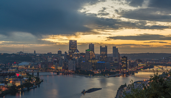 A barge rolls by Pittsburgh at dawn from the West End