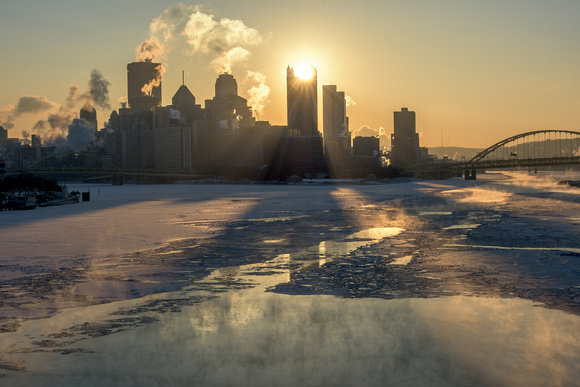 Sunlight streams through downtown Pittsburgh at dawn in the winter