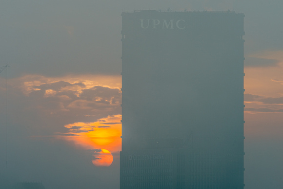 The sun burns bright beside the Steel Building through the fog in Pittsburgh