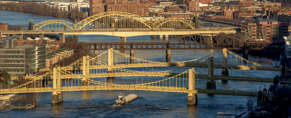 A barge passes under the Sister Bridges in Pittsburgh at dusk