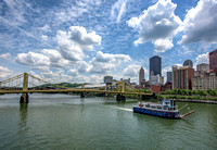A boat from the Gateway Clipper glides under painted clouds in Pittsburgh