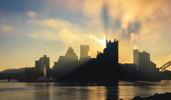 Sunlight cuts through the fog and illuminates the fountain in Pittsburgh