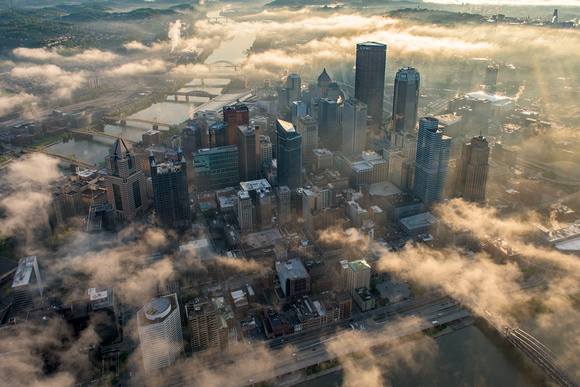 Sun rays burst through the fog in this aerial view of Pittsburgh at dawn