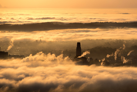 A silhouetted Cathedral of Learning rises into the fog above Pittsburgh