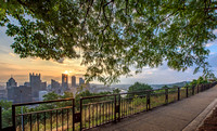 Trees frame the Pittsburgh skyline and Grandview Avenue at dawn