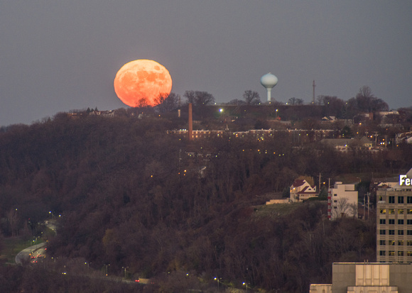 A full moon sits on the horizon of Pittsburgh