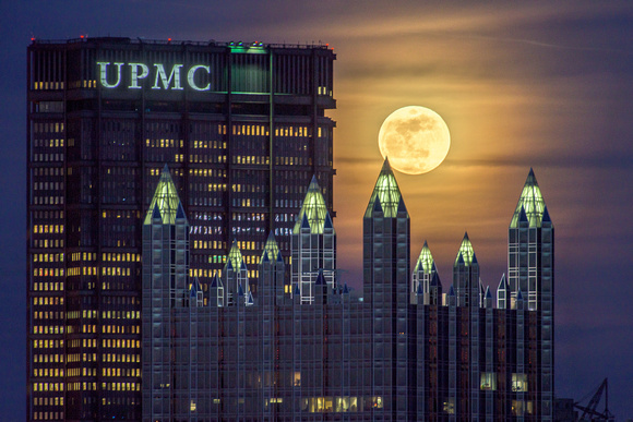 A spire from PPG Place pierces the full moon in Pittsburgh