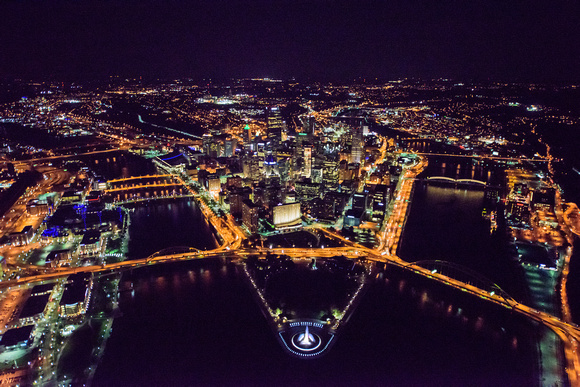 Pittsburgh glows at night in an aerial view from above the Ohio