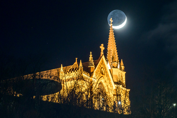 The crescent moon is intersected by the spire of St. Mary of the Mount in Pittsburgh