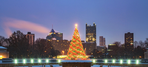 The Christmas tree at the Point shines in front of the Pittsburgh skyline