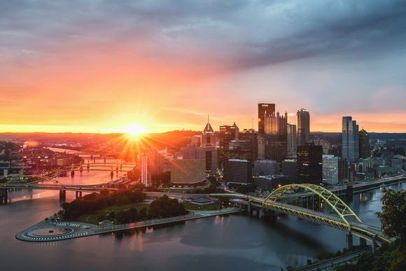 The sun shines through the clouds over Pittsburgh at dawn