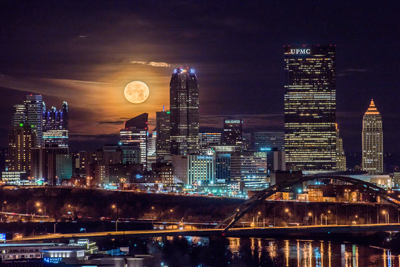 The near full moon sets behind the Pittsburgh skyline in the early morning hours