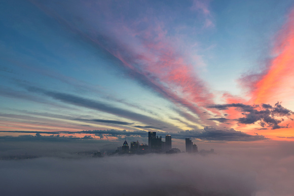 Beautiful clouds rise into the sky over a fog enveloped city
