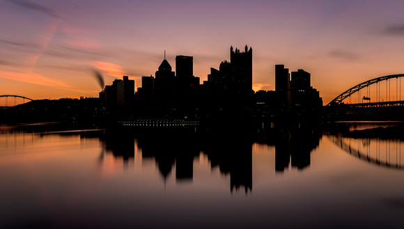 A silhouetted Pittsburgh skyline reflects in the Ohio River at dawn