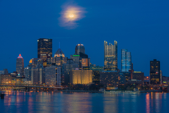 The full moon glows through the clouds over Pittsburgh