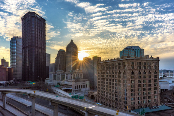 Sun bursts through the Pittsburgh skyline at dusk