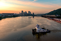 A barge turns on the Ohio River at dawn in Pittsburgh