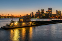 A barge glows at dawn from the South Shore of Pittsburgh