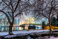 A beautiful winter scene on the North Shore of Pittsburgh, as trees frame the Clemente Bridge