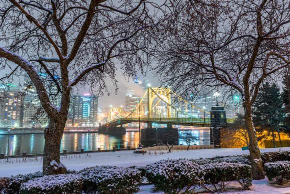 A beautiful winter scene on the North Shore of Pittsburgh, as trees frame the Clemente Bridge