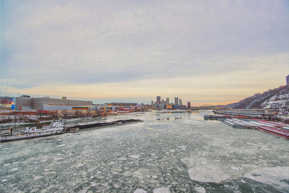 Wide angle barge on the icy Ohio River with the Pittsburgh skyline in the background