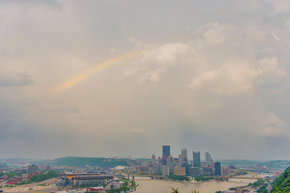 A rainbow begins to form over the Pittsburgh skyline