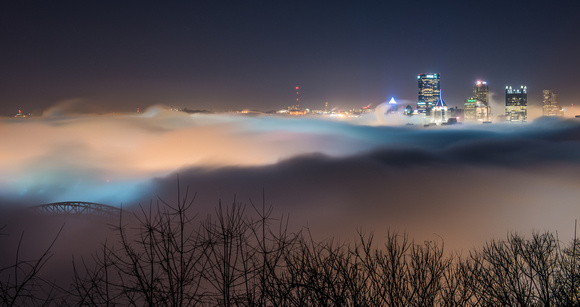 The PIttsburgh skyline and West End Bridge rise up from the fog