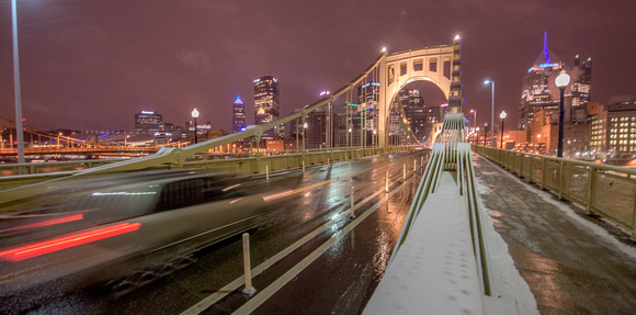 Cars streak by in the snow on the Clemente Bridge in Pittsburgh