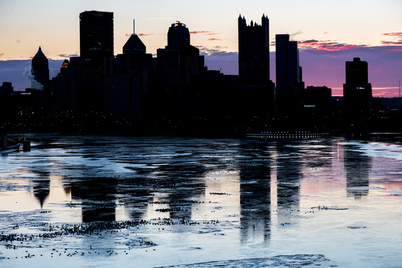 A silhouette Pittsburgh reflects in the river