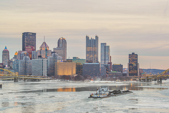 Barge in front of Pittsburgh skyline at dusk on the icy Ohio River from the West End Bridge