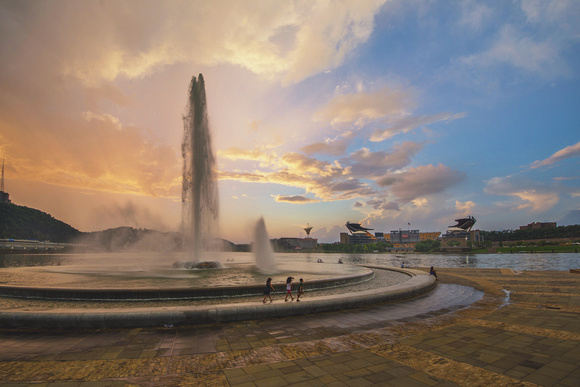 People walking by the fountain in Pittsburgh during a beautiful sunset