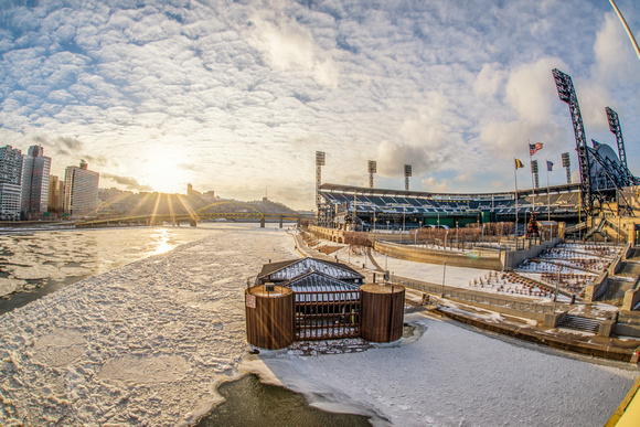 PNC Park at sunset behind an ice covered Allegheny River in the winter in Pittsburgh