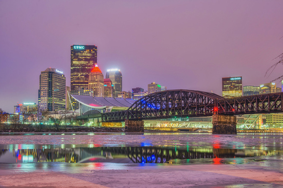 Purple Pittsburgh skyline by the icy Allegheny River before the sun comes up