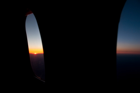 A sunrise and silhouetted windows from an airplane