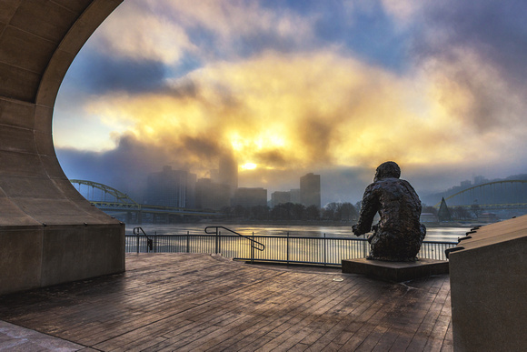 Light breaks through the fog over the Mr. Rogers statue at dawn