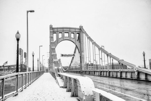 A snowy walkway along the Roberto Clemente Bridge in Pittsburgh B&W