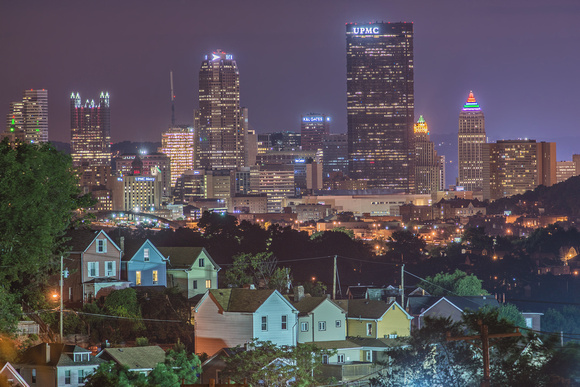 Pittsburgh skyline rises over Greenfield houses at night